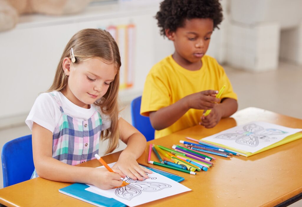 Colouring is a great sitting still activity. Shot of preschool students colouring in class.